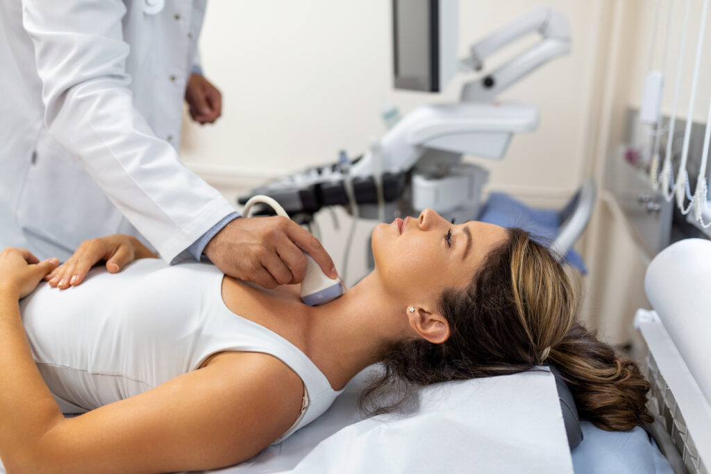Doctor making ultrasound of thyroid gland to woman patient in clinic. Diagnosis and treatment of autoimmune thyroiditis concept
